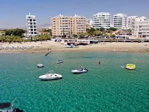 eine Gruppe von Booten im Wasser in der Nähe eines Strandes in der Unterkunft The Ciao Stelio Deluxe Hotel (Adults Only) in Larnaka