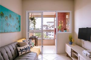 a living room with a couch and a large window at VARANDA GOURMET c churrasqueira-3 quartos- Wi-fi in Bertioga