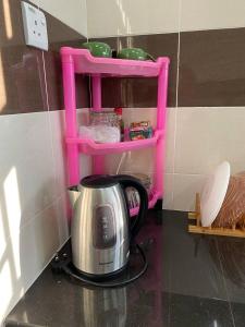 a tea kettle on a counter with a pink shelf at dRose Homestay in Kuala Terengganu
