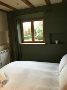 a bedroom with a white bed and a window at Farmhouse B&B in Saint-Georges