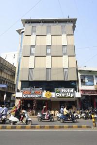 a group of people riding scooters in front of a building at Hotel One Up in Ahmedabad