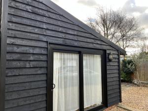 un cobertizo negro con una ventana y una puerta en Studio Annex en Cottenham