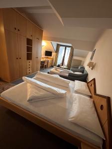 uma cama grande com almofadas brancas num quarto em Hotel Brandl em San Candido