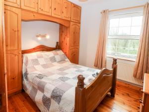 a bedroom with a wooden bed and a window at Raheen in Castletownshend