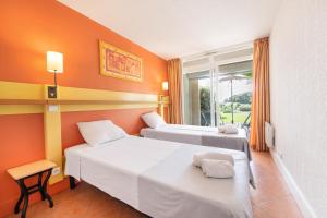 2 Betten in einem Zimmer mit orangefarbenen Wänden in der Unterkunft SOWELL RESIDENCES Les Sablons in Le Grau-du-Roi