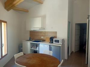 eine kleine Küche mit einem Tisch und einer Mikrowelle in der Unterkunft Le clos du pin in Thèzan-lès-Béziers