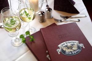 a table with wine glasses and a book on it at Hotel an der Sonne & Restaurant Zum Schneiger in Schönwald