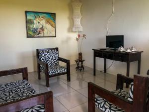 a living room with a desk and chairs and a table at Villa Velha Flats in Itamaracá