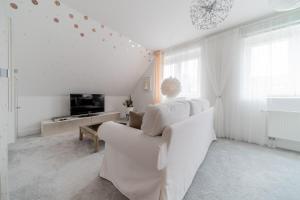 a white living room with a couch and a tv at Privatapartment in Laatzen