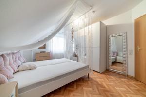 a white bedroom with a bed and a mirror at Privatapartment in Laatzen