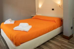 ein Bett mit orangefarbener Bettwäsche und weißen Handtüchern darauf in der Unterkunft Appartamento Roma 55 in Mantua