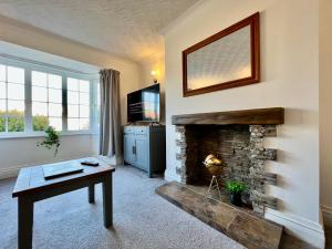 a living room with a fireplace and a table at Curzon House Two - Serene Escape Cottage in Cleethorpes