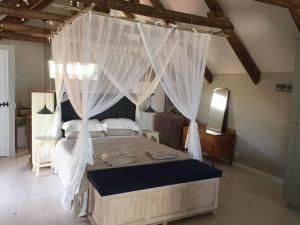 ein Schlafzimmer mit einem Himmelbett mit weißen Vorhängen in der Unterkunft Living The Breede - Infanta Loft in Infanta