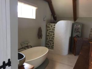 ein Badezimmer mit einer weißen Badewanne und einem Waschbecken in der Unterkunft Living The Breede - Infanta Loft in Infanta