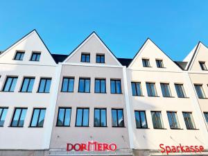 a white building with a red sign in front of it at DORMERO Hotel Hersbruck in Hersbruck