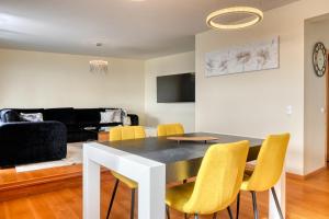 a living room with a dining room table and yellow chairs at Villa 58, a Home in Madeira in Santa Cruz