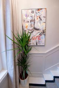 a potted plant in a room with a painting at Haus of Mason in London