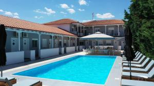 a swimming pool in front of a building with an umbrella at Philoxenia Suites in Nea Vrasna