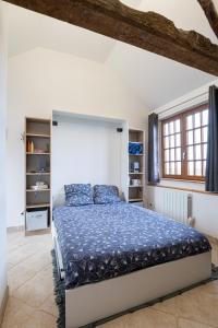 a bedroom with a large bed with a blue comforter at La Bouillerie du Manoir des Bréholles in Goustranville