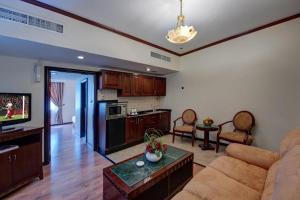 a living room with a couch and a kitchen at Royal Tulip Apartments in Sharjah