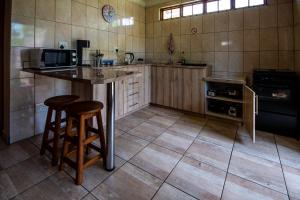 una cucina con bancone e 2 sgabelli da bar di Invite Guest House Self Catering Accommodation a Vanderbijlpark