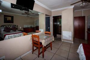 a room with a table and chairs and a bedroom at Invite Guest House Self Catering Accommodation in Vanderbijlpark