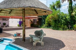 a chair and an umbrella next to a pool at Invite Guest House - Self Catering Accommodation in Vanderbijlpark in Vanderbijlpark