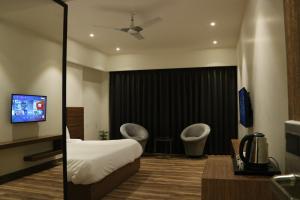 a hotel room with a bed and chairs and a tv at Hotel The Sawai in Jaipur