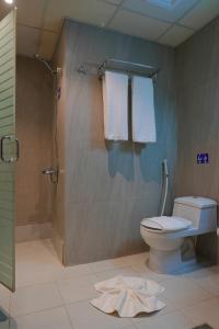 ein Bad mit einer Dusche, einem WC und Handtüchern in der Unterkunft Saraya Al Deafah Hotel in Mekka