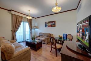 a living room with a couch and a tv at Royal Tulip Apartments in Sharjah