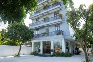 a white building with balconies and trees at Nhà Nghỉ Ngọc Anh in Nghĩa Lộ