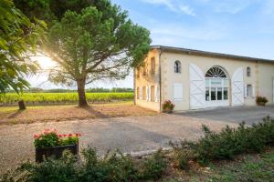 a building with a tree in front of a field at Airial de Tourteau Chollet in Arbanats
