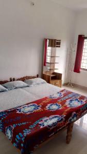 a bedroom with a bed with a colorful blanket on it at Thekkekara Tourist Home Vagamon in Vagamon