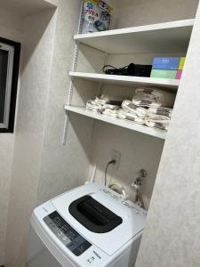 a washing machine in a bathroom with a shelf at shizuka1 501 in Osaka