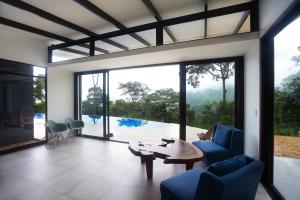 sala de estar con sillas azules y mesa en Costa Rican Jungle Experience, en Tinamaste