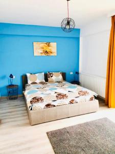 - une chambre dotée d'un lit avec un mur bleu dans l'établissement Apartament Mara Centru, à Alba Iulia