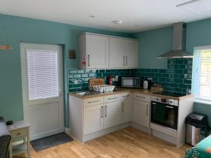 a kitchen with white cabinets and green tile on the walls at Walnut Lodge, Timberland in Martin