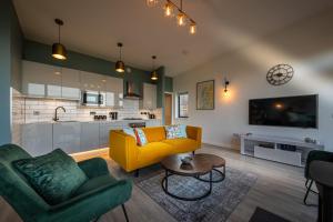 a living room with a yellow couch and a kitchen at Silverwood Waternish in Portree +37 photos