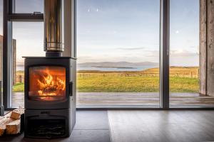 a fireplace in a room with a view of a field at Silverwood Waternish in Portree
