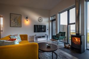 a living room with a yellow couch and a wood stove at Silverwood Waternish in Portree