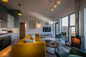 a living room with a yellow couch and a fireplace at Silverwood Waternish in Portree