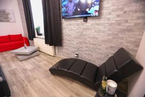 a living room with a couch and a tv on a brick wall at Wellnes apartmán Leqwell in Uherský Brod