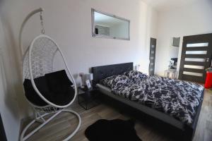um quarto com uma cama e uma cadeira suspensa em Wellnes apartmán Leqwell em Uherský Brod