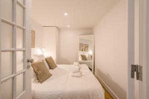 里斯本的住宿－Alfama Chic Penabuquel，白色卧室配有带白色床单和枕头的床
