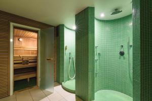 W łazience z prysznicem znajdują się ściany wyłożone zielonymi kafelkami. w obiekcie Hotel Gasthof Brandstätter w mieście Salzburg