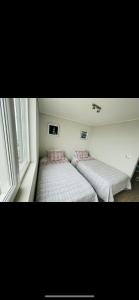 two beds in a room with two windows at Hermoso departamento Viña del Mar in Viña del Mar