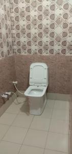 a bathroom with a toilet and a tile wall at Hotel A Star & Restaurant By WB Inn in Ghaziabad