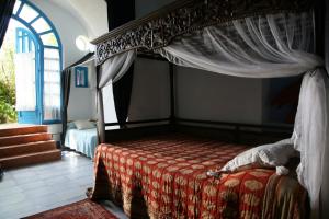 a bedroom with a canopy bed with a red blanket at Dimora Coloniale B&B in Forio d'Ischia