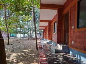 a red brick building with trees in front of it at Palm Beach Resort in Kumta