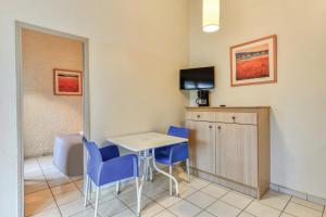 een kamer met een tafel en stoelen en een televisie bij SOWELL Family Cap d’Agde in Cap d'Agde